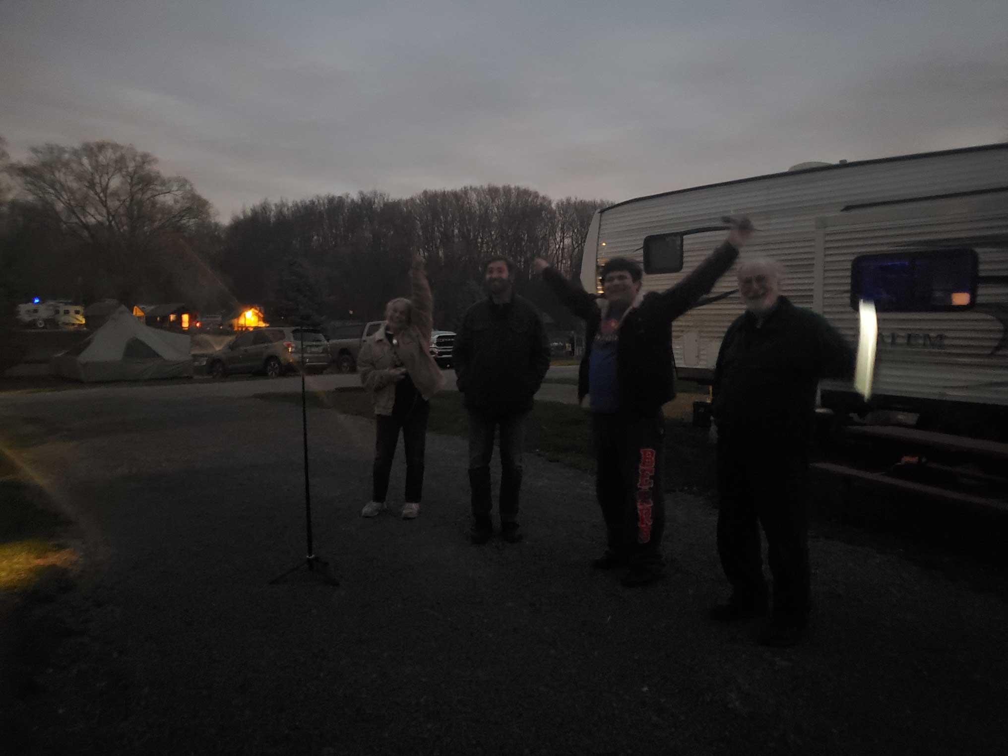 people stand in front of an RV in semi-darkness