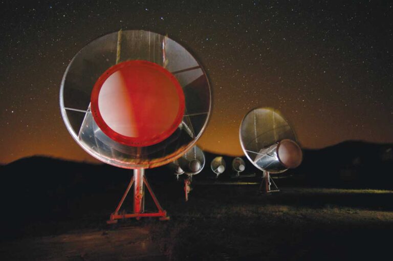 several large satelitte dishes pointing to the sky with the night sky in the background