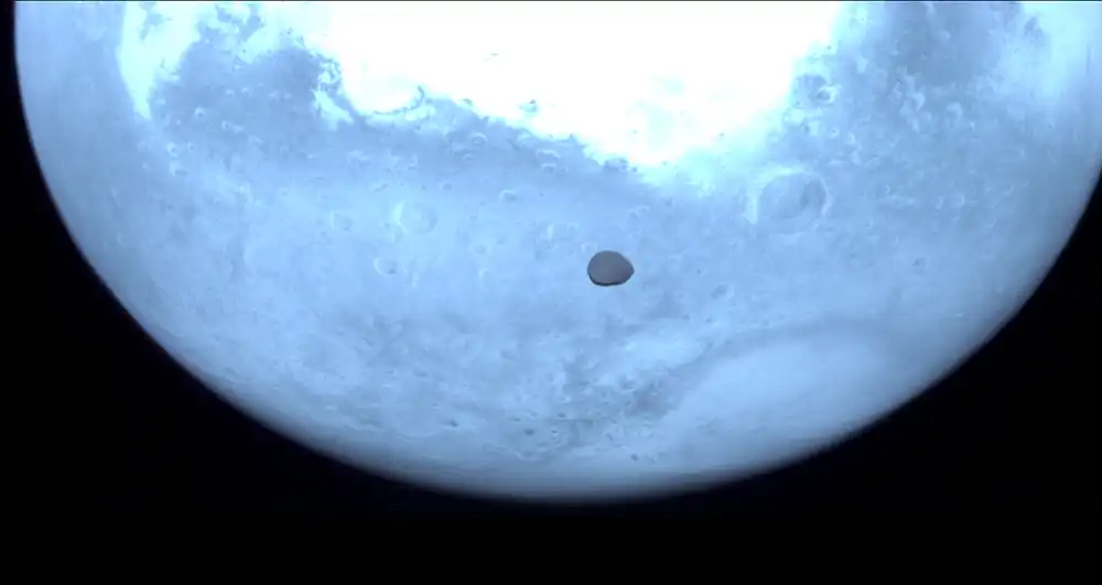 Mars appears blue in the background, while small Deimos in the foreground appears dark gray