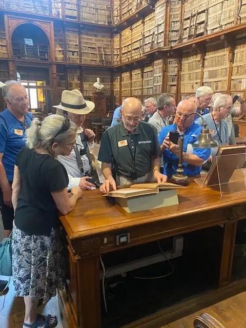 Tour group stands around desk. A book lies open on a stand on the desk