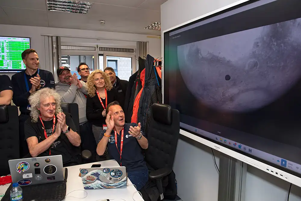 applauding people near TV screen showing flyby image