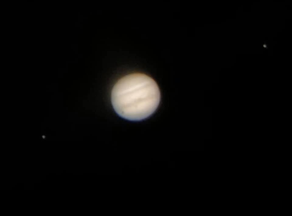 Jupiter as it appears in a small to medium telescope. Tim Dearing of the Louisville Astronomical Society grabbled this shot with an iPhone through the eyepiece of an 8-inch Dobsonian scope in early 2021. The Jovian moon at left casts its tiny shadow onto Jupiter.