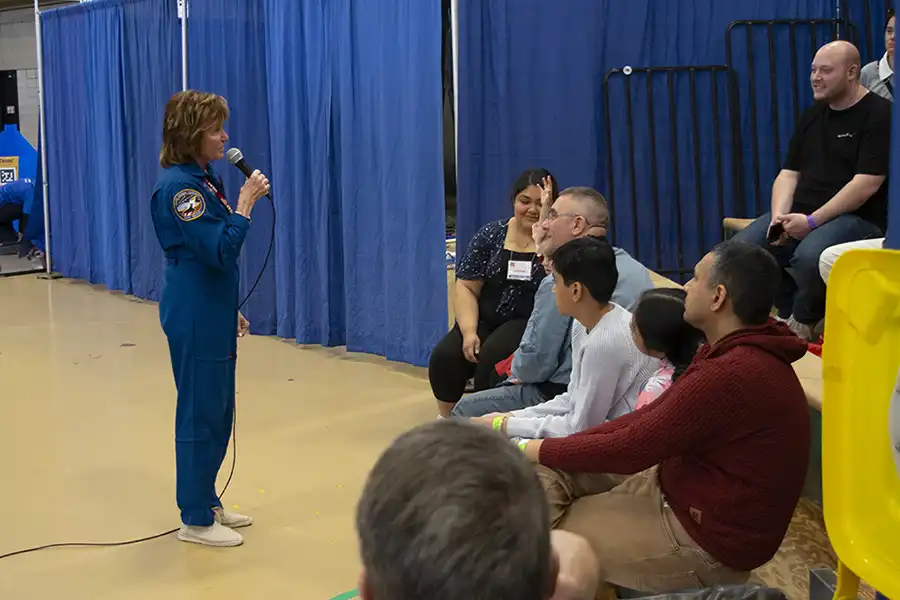 Astronaut in blue suit talks to audience
