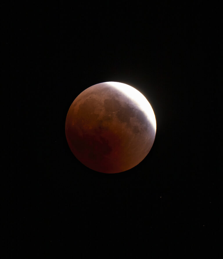 Partially eclipsed Moon - red with a crescent of silver