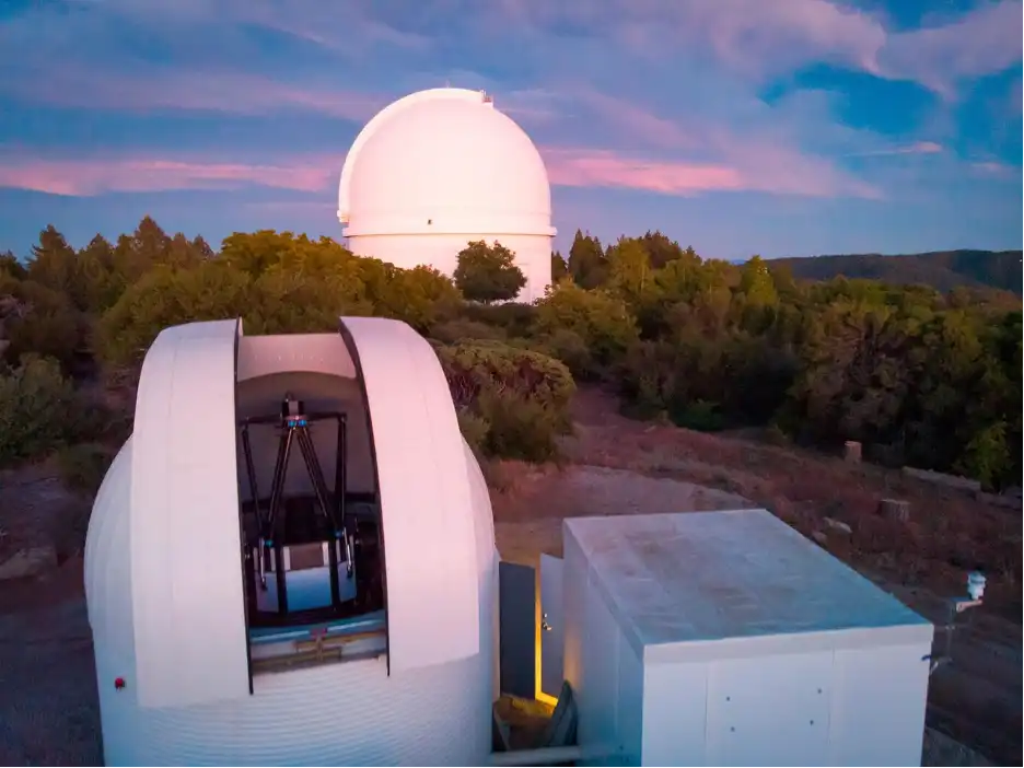 Two telescope domes gleam white against a sunset sky