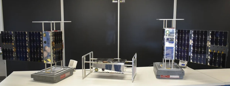 EZIE CubeSats on a table, one on its side in the middle, the other tall on either side
