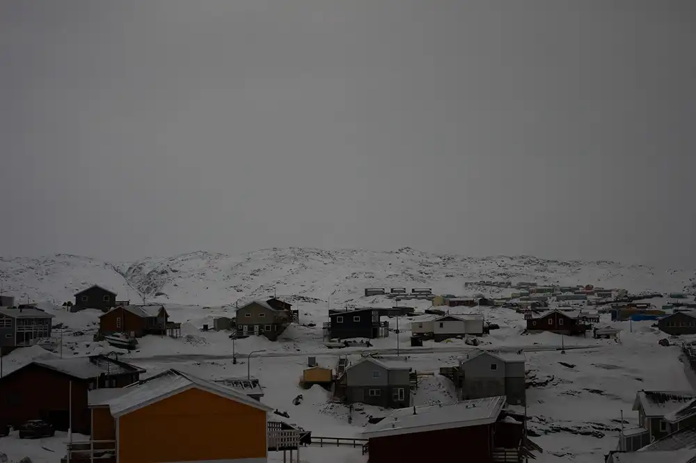 Darkened cloudy skies over a snow-covered landscape dotted with houses
